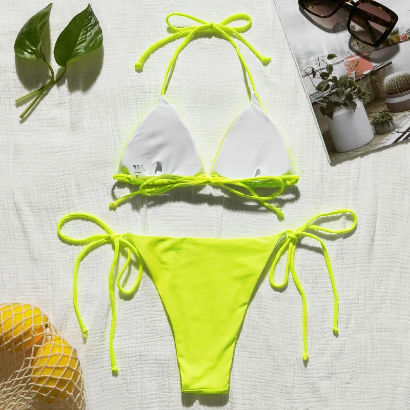 Bikini hai mảnh trắng và xanh neon đặt trên khăn sáng màu