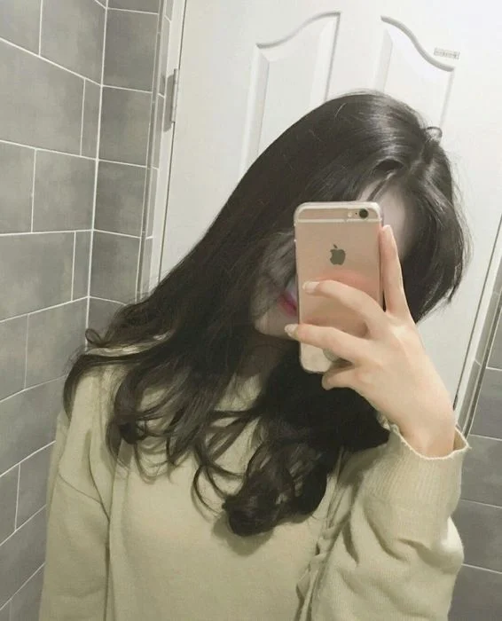 Cô gái xinh đẹp chụp ảnh gái che mặt bằng điện thoại trước gương