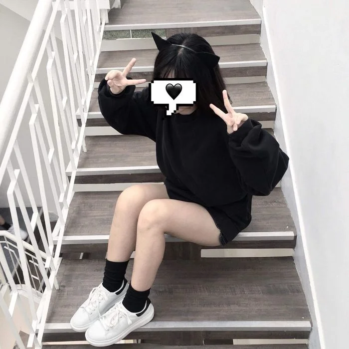 Cô gái mặc áo hoodie đen ngồi cầu thang che mặt