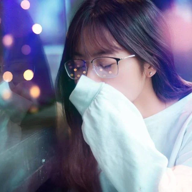 Cô gái đeo kính che miệng bằng tay